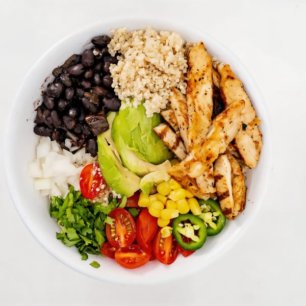 A colorful Dale Arepa Bar bowl with grilled chicken, black beans, quinoa, avocado, corn, and vegetables.