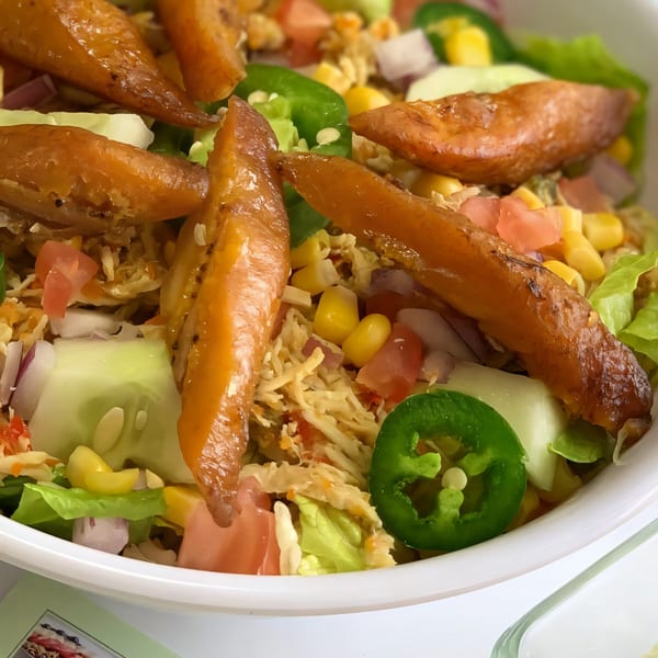 Close-up of a Venezuelan salad with plantains, corn, tomatoes, onions, cucumbers, and jalapeños.