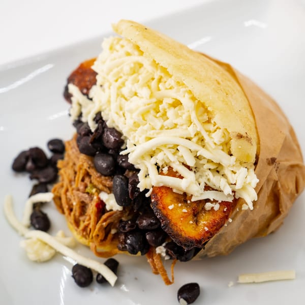 Venezuelan arepa filled with shredded beef, black beans, fried plantains, and shredded white cheese.