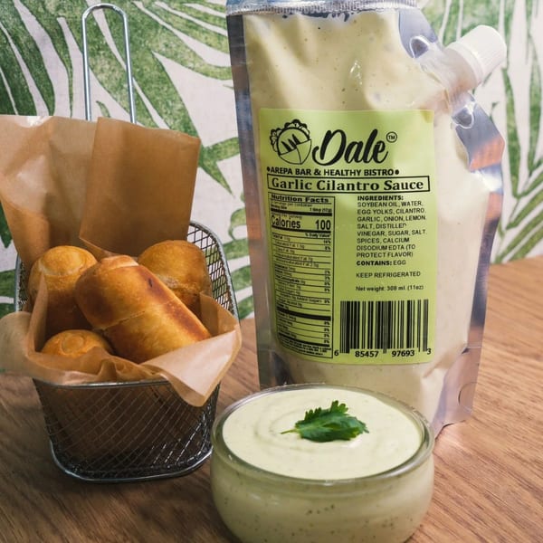 Dale Arepa Bar's garlic cilantro sauce in a pouch and bowl, with fried tequeños in a basket.